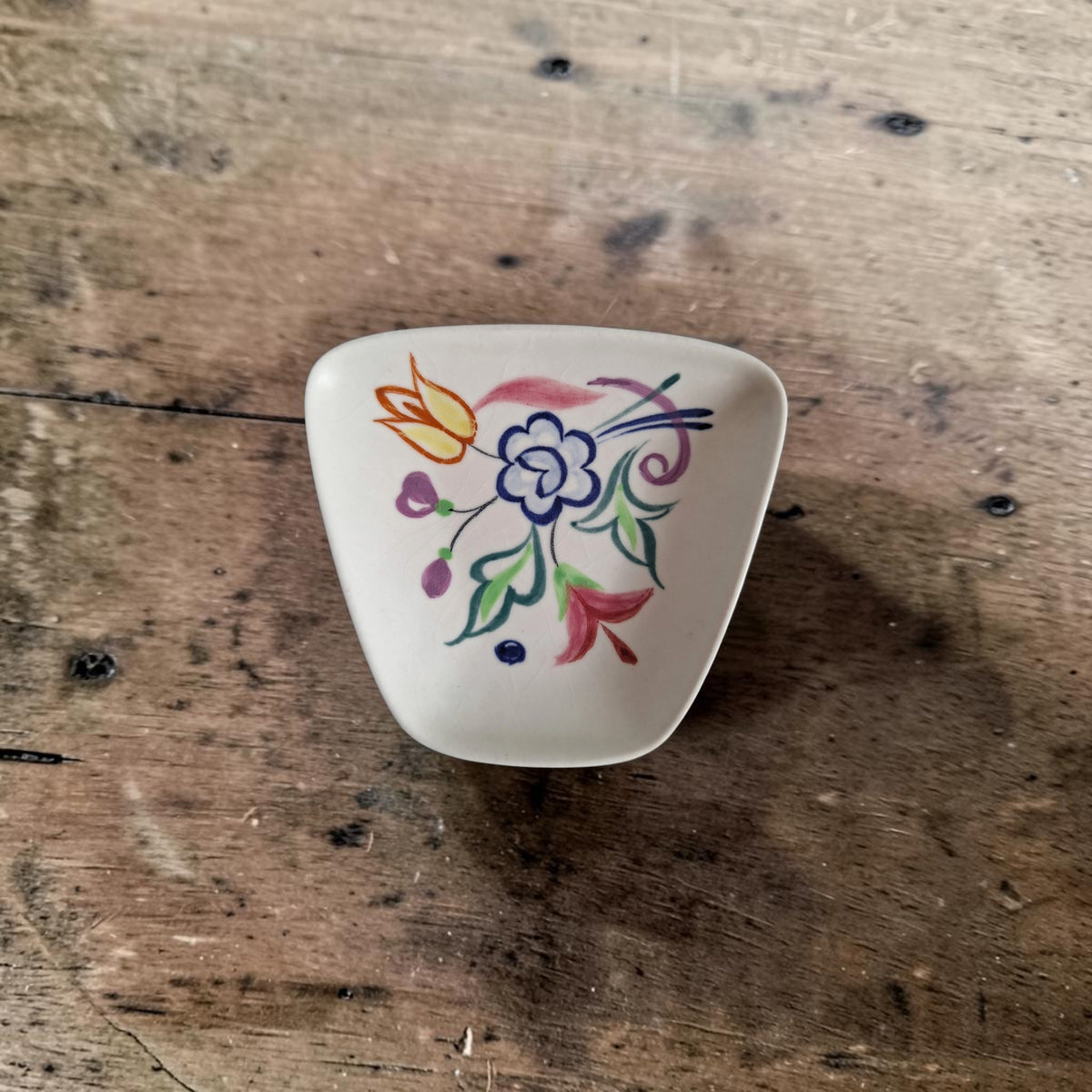 Handgeschilderd aardewerken schaaltje van Poole Pottery, model 41, met een BN-bloemendecor op een eierschaalwitte ondergrond.