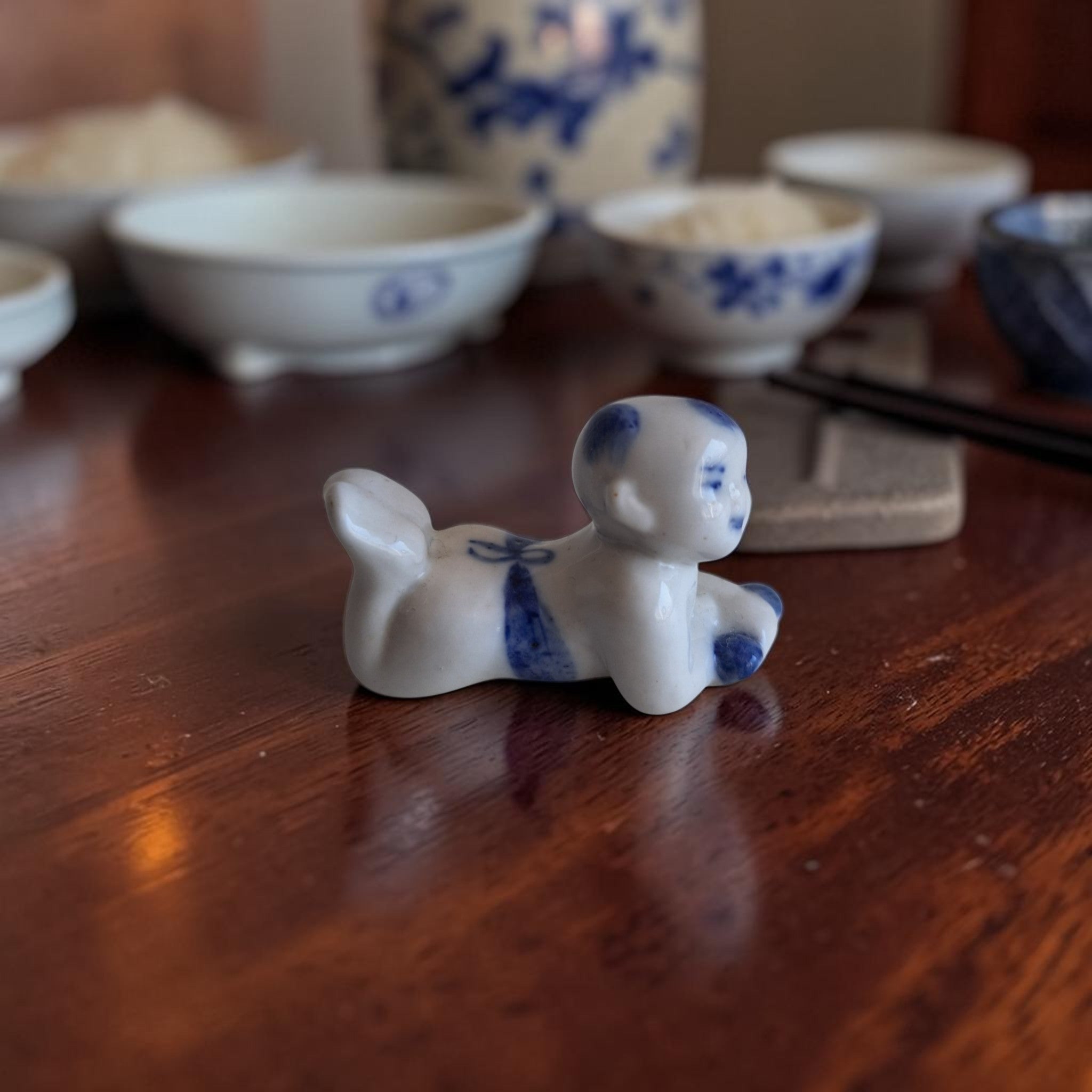 Chinees blauw-wit porseleinen miniatuurbeeldje van een kruipende Karako jongen, hoogte ca. 4 cm, eetstokjeshouder of decoratief object.