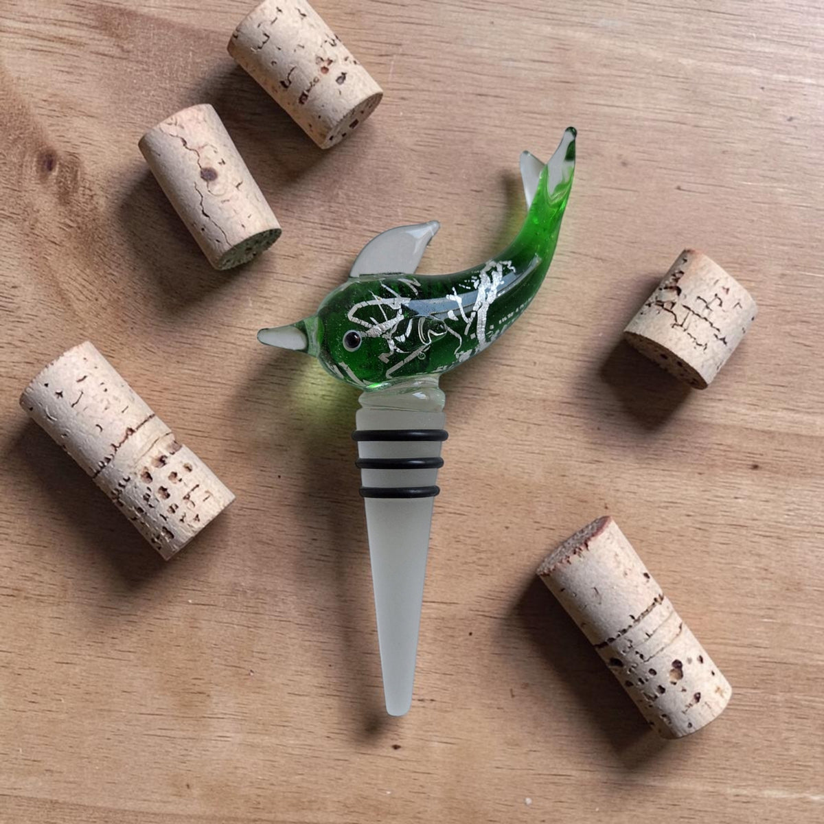 Groene glazen flesstopper in de vorm van een springende dolfijn met decoratieve accenten, uitgevoerd in Murano-stijl.
