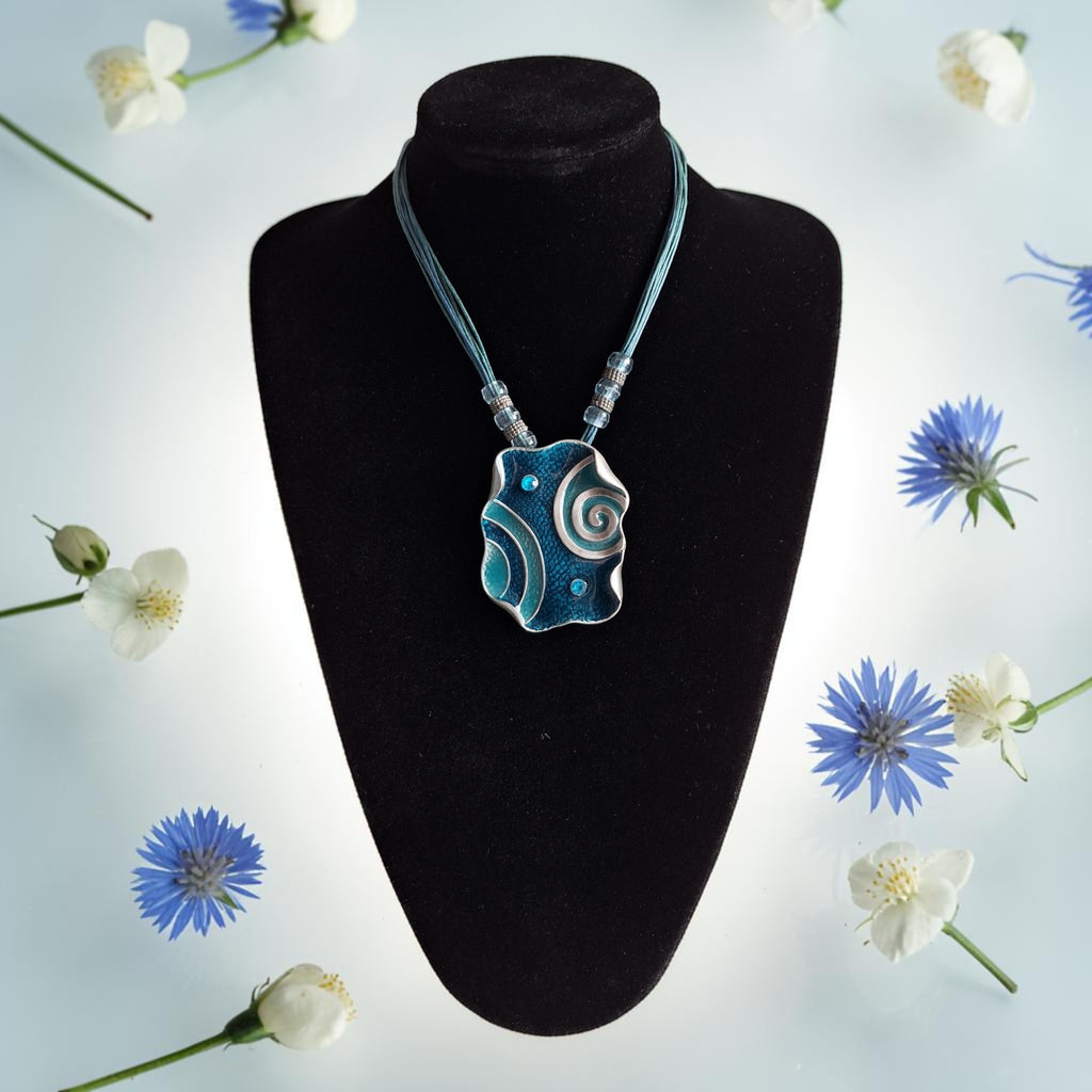 Ketting met blauwe metalen hanger, spiraalmotieven en meerstrengs koord, totale lengte 51cm
