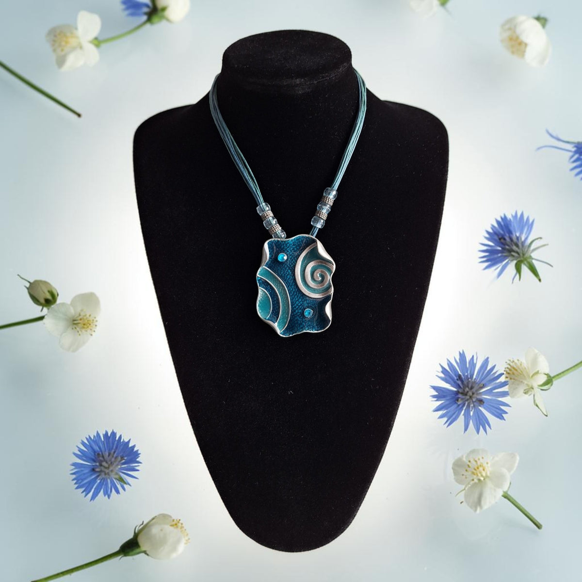 Ketting met blauwe metalen hanger, spiraalmotieven en meerstrengs koord, totale lengte 51cm
