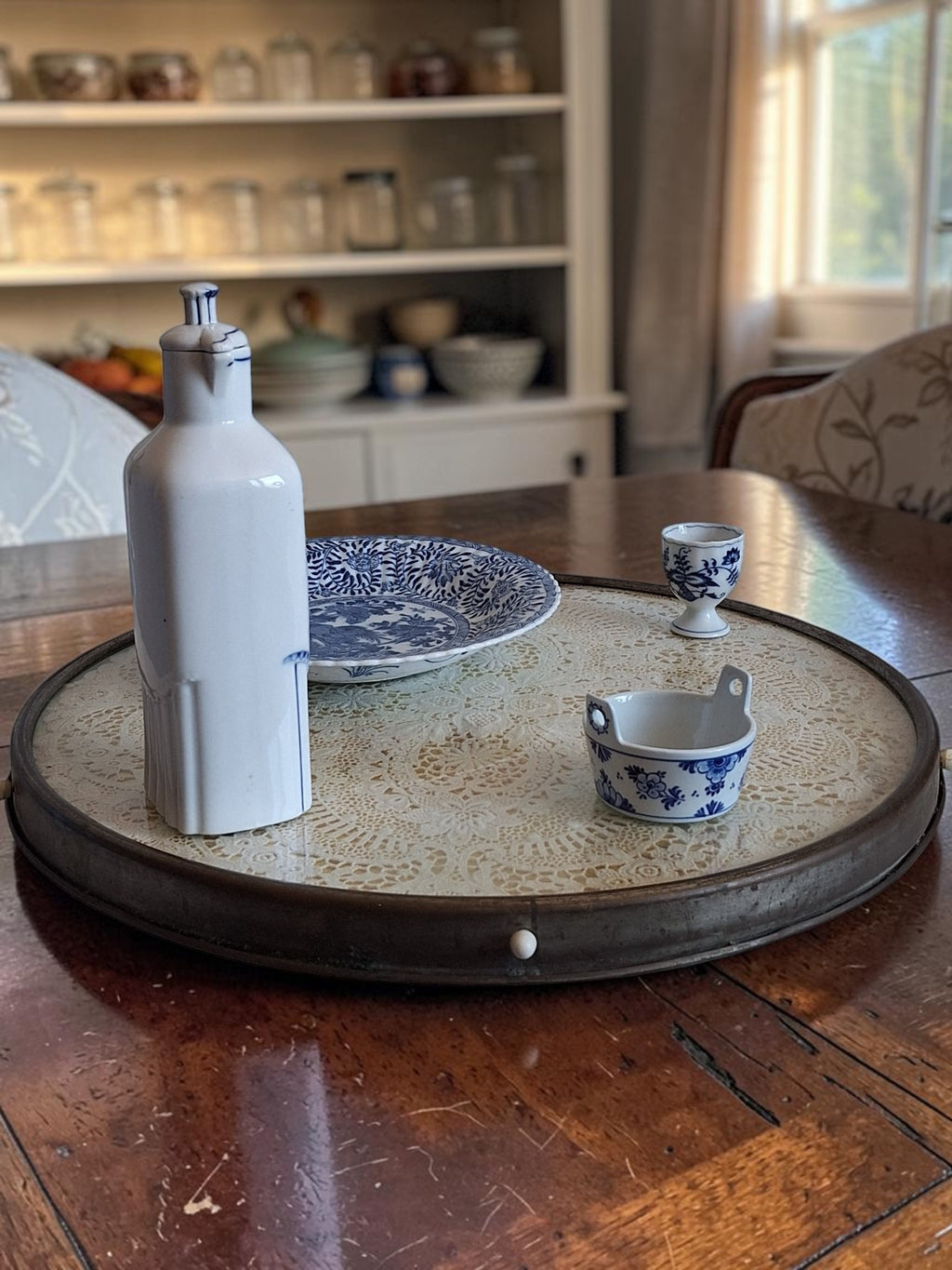 Antiek Art Deco draaitableau (Lazy Susan) met handgewerkt kanten kleedje onder een glazen blad, verchroomde rand en houten bodem, circa jaren '20–'30.