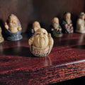 Miniatuur netsuke-stijl beeldje van een lachende wijsgeer met kaal hoofd, lange baard en kalligrafie op het ivoorkleurige gewaad.