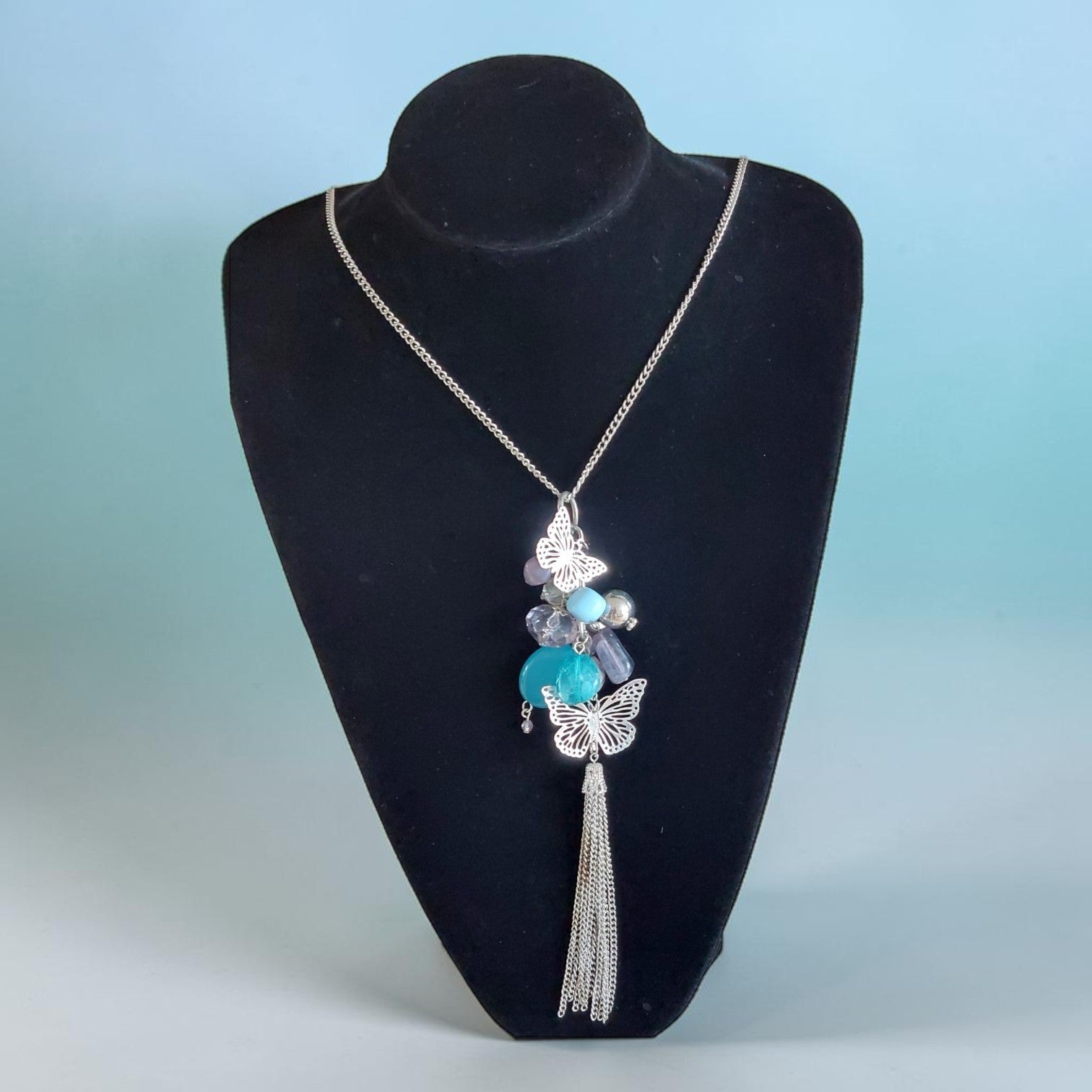 Lange zilveren halsketting met turquoise en grijze kralen, twee sierlijke zilveren vlinders en een elegante kettingkwast, 86 cm.