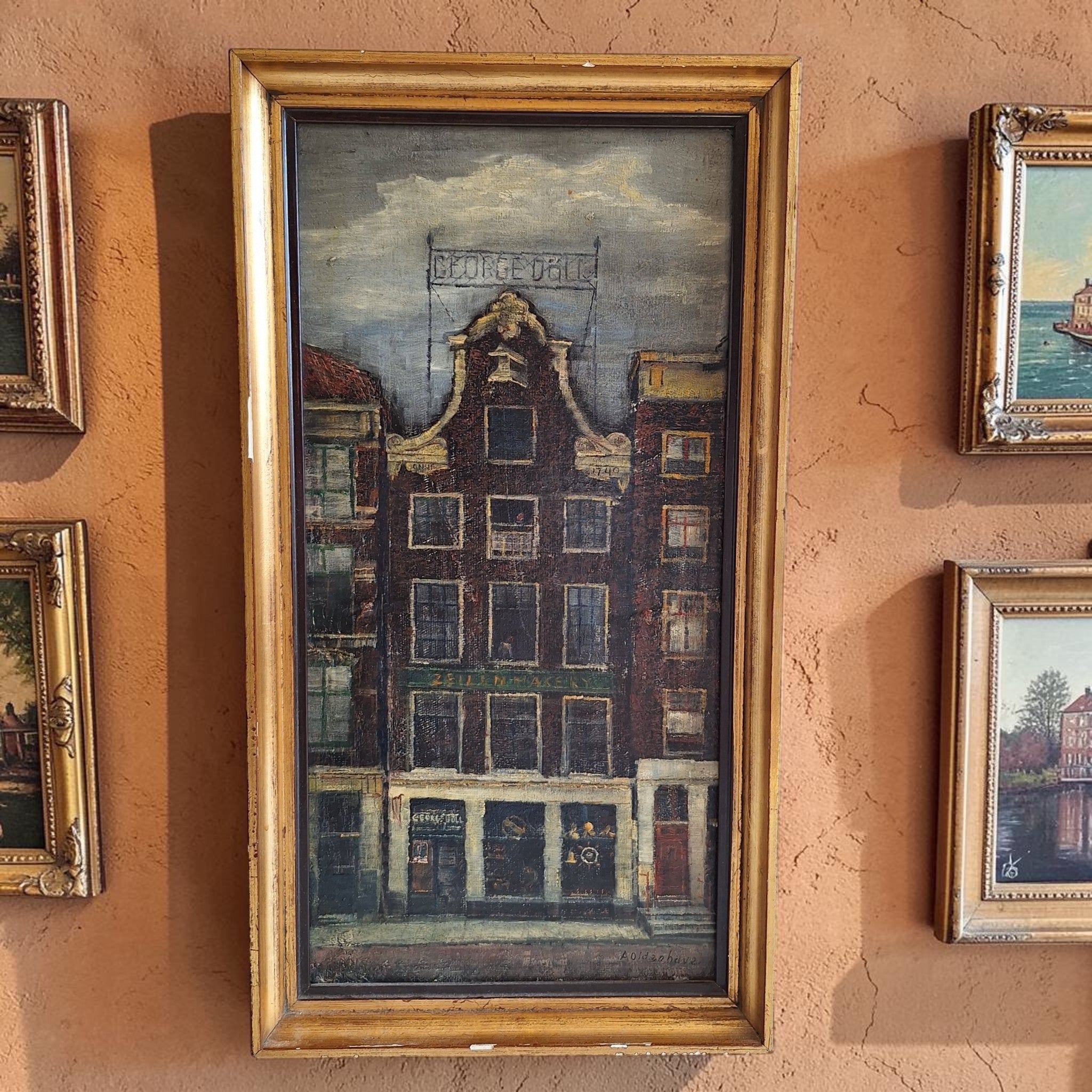 Gesigneerde olieverf op board van A. Oldenhove met een realistisch Amsterdams grachtenpand aan de Prins Hendrikkade, voormalige zeilmakerij George Uhl, 43×23 cm.