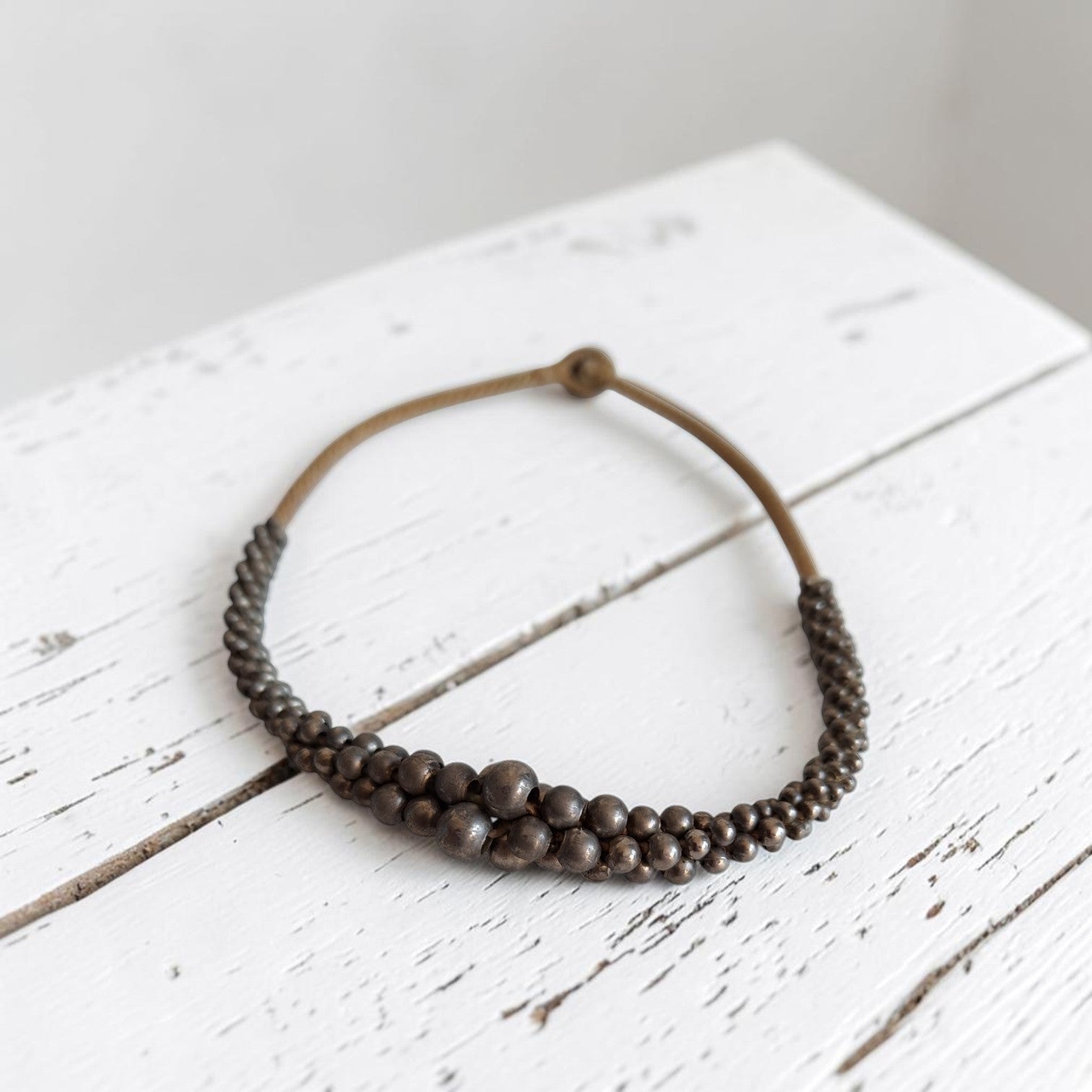 Vintage bronskleurig houten kralencollier met bolletjes in verschillende maten op touw geregen, lengte 44 cm.
