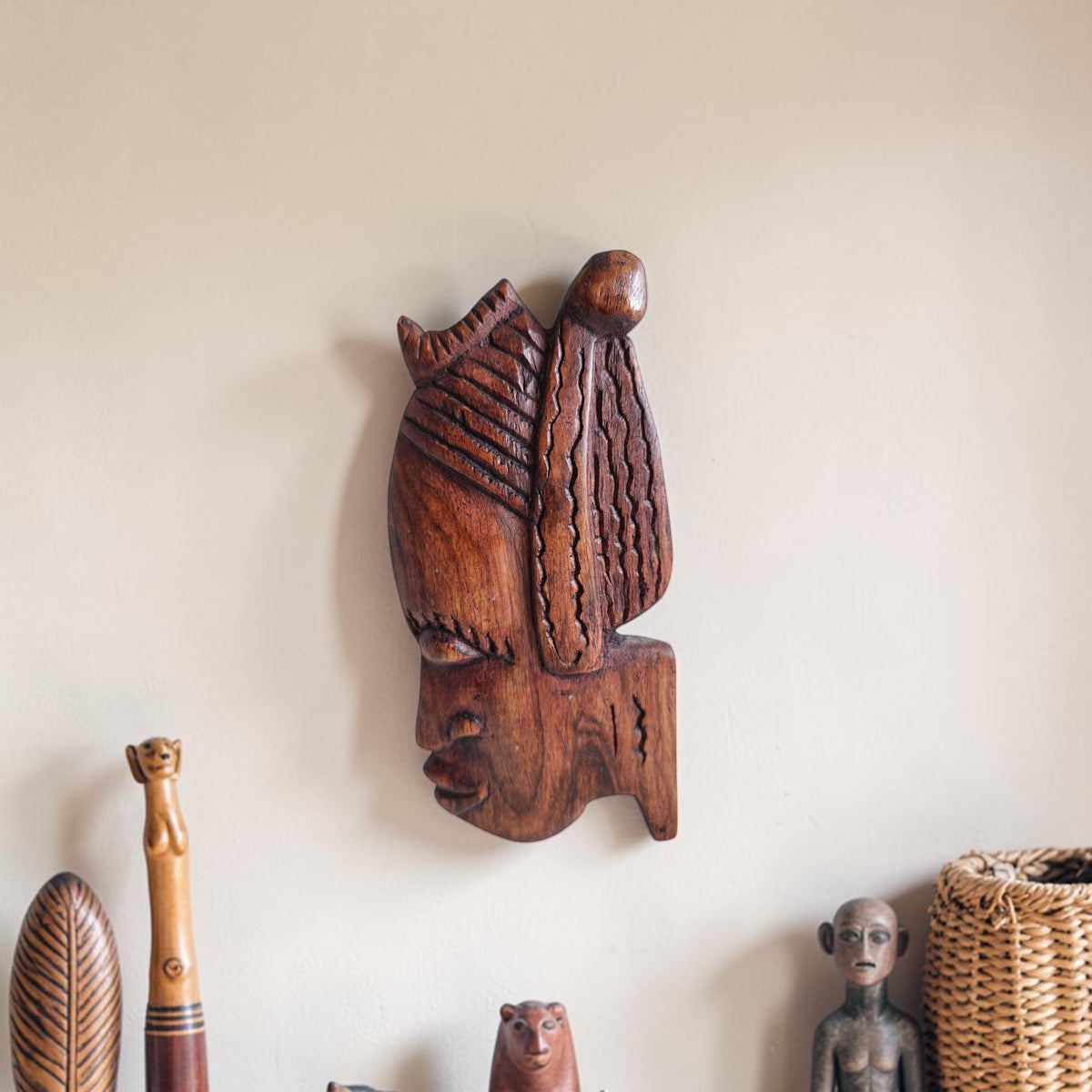 Handgesneden houten wanddecoratie van een gestileerd vrouwenhoofd in profiel met uitgesneden lineaire patronen en een gedetailleerd haardecor.

