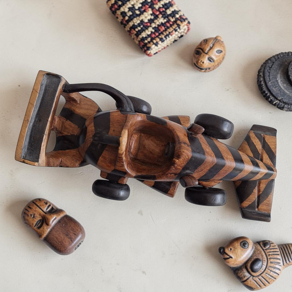 Houten racewagen met contrasterende donkere en lichte banen, uitgevoerd als decoratief Afrikaans snijwerk.
