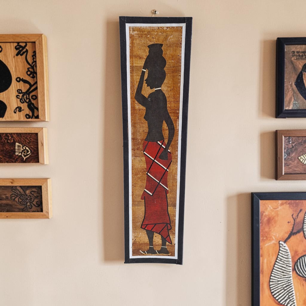 Langwerpige bananenbladcollage met het silhouet van een Afrikaanse vrouw die een kruik op haar hoofd draagt.

