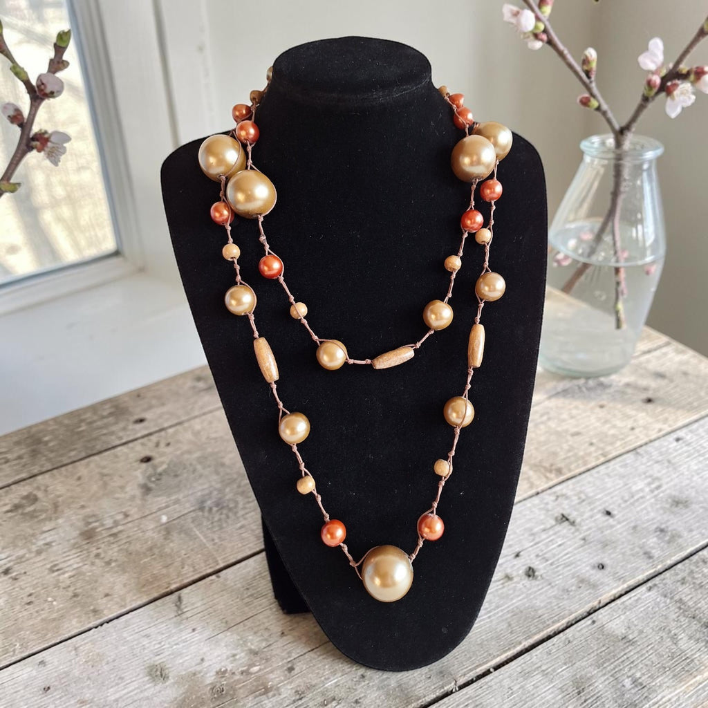 Vintage lange kralenketting met mix van houten kralen in goud- en koperkleurige tinten, lengte 122 cm.