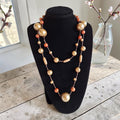 Vintage lange kralenketting met mix van houten kralen in goud- en koperkleurige tinten, lengte 122 cm.