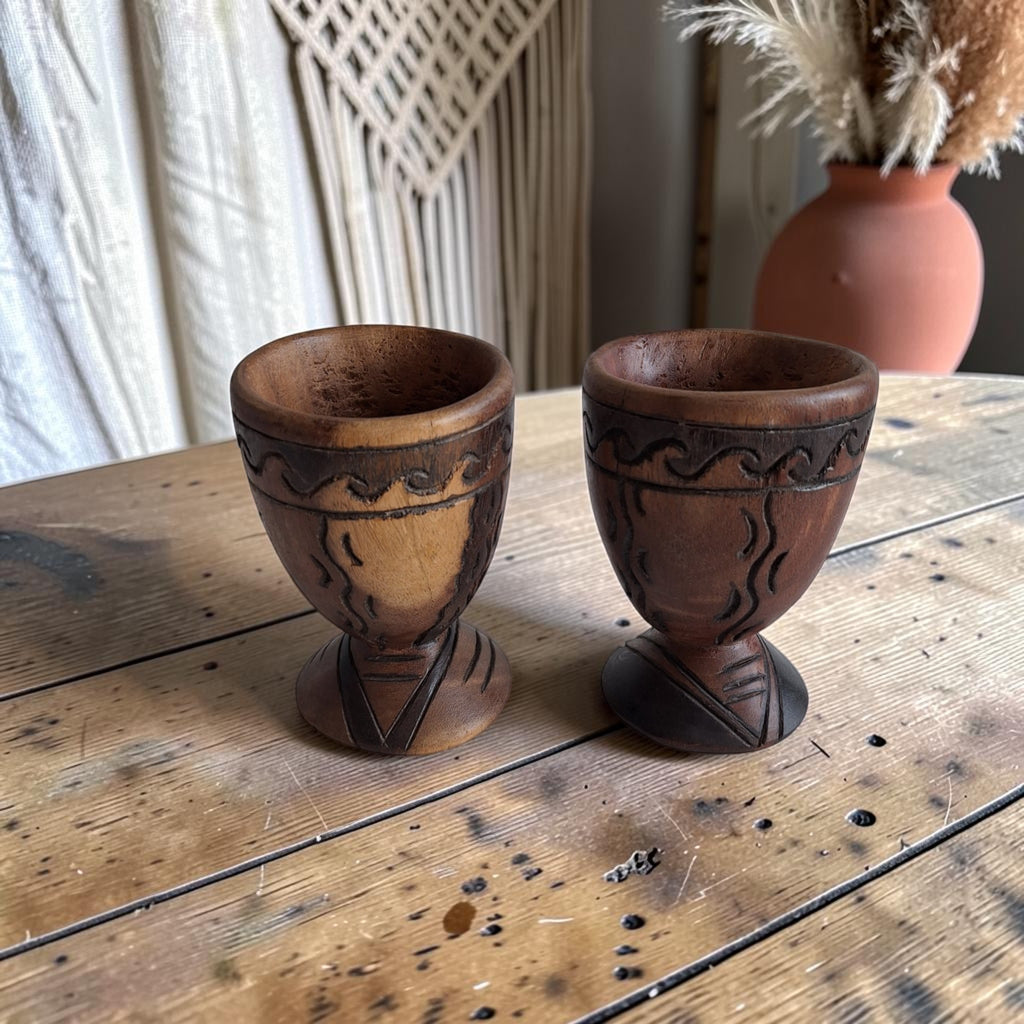 Twee houten kelken met golvend geometrisch snijwerk en driehoekige motieven
