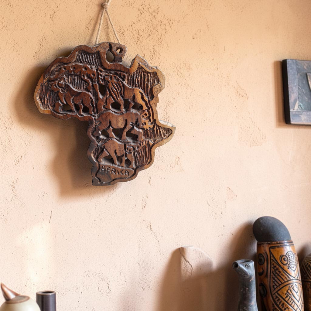 Handgemaakte houten kaart van Afrika met gegraveerde silhouetten van een olifant en een leeuw en het opschrift Africa onderaan.
