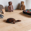 Handgesneden schildpadbeeldje van donker hout met een glad afgewerkte bovenkant en zichtbare houtnerf.
