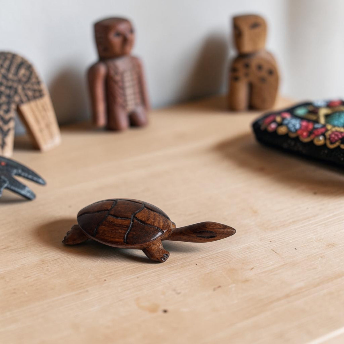 Handgesneden schildpadbeeldje van donker hout met een glad afgewerkte bovenkant en zichtbare houtnerf.
