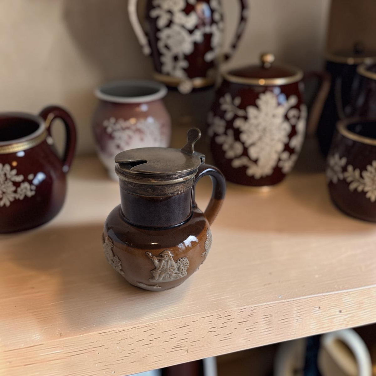 Doulton Lambeth mosterdpotje van tweekleurig steengoed met crèmekleurige reliëfscènes en een verzilverd EPNS-deksel.