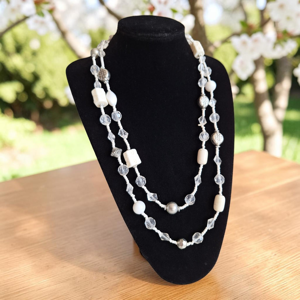 Vintage dubbelstrengige lange kralenketting met afwisseling van witte en transparante kralen, lengte 140 cm.
