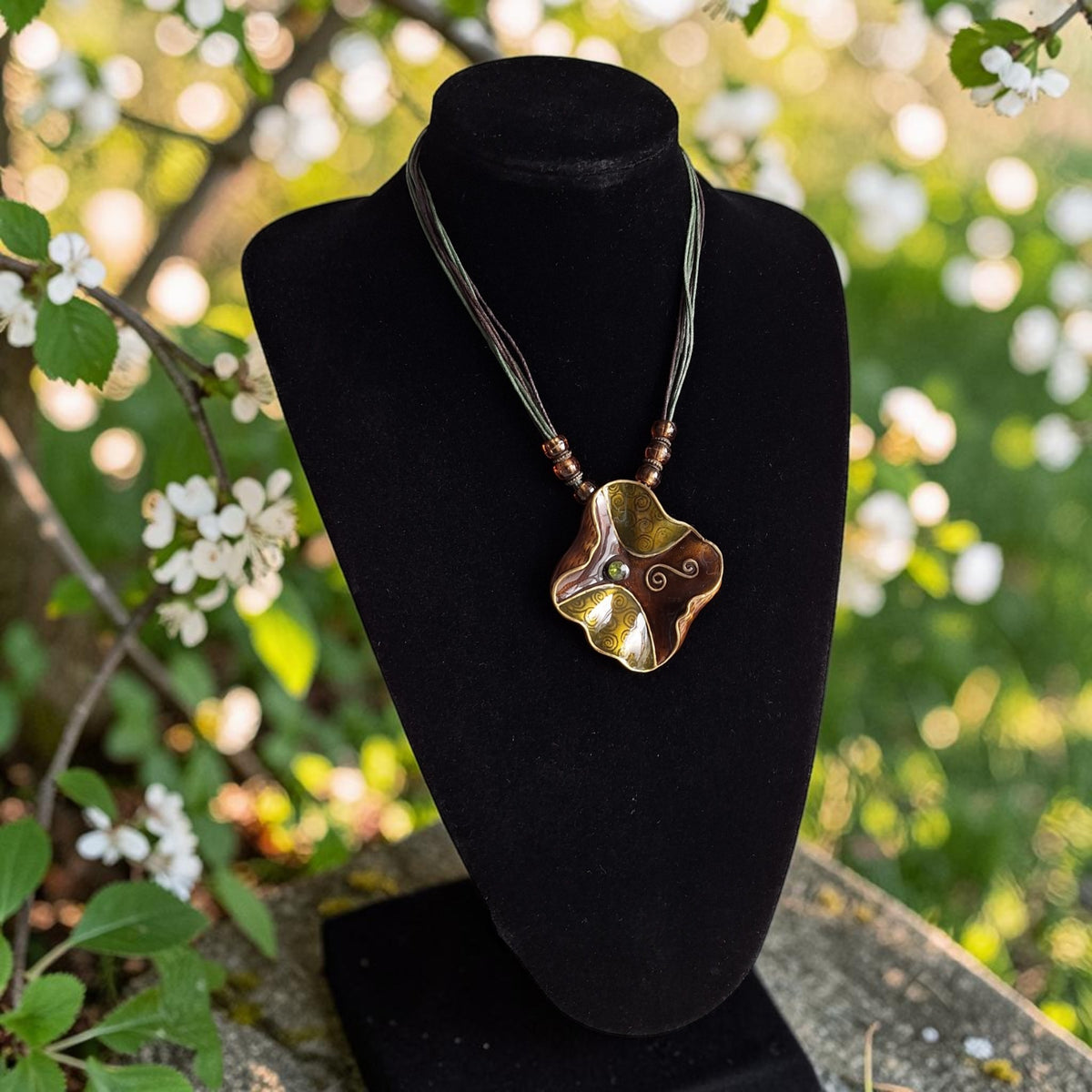Koordketting met grote abstracte metalen hanger en groen steentje in het midden, totale lengte 51cm
