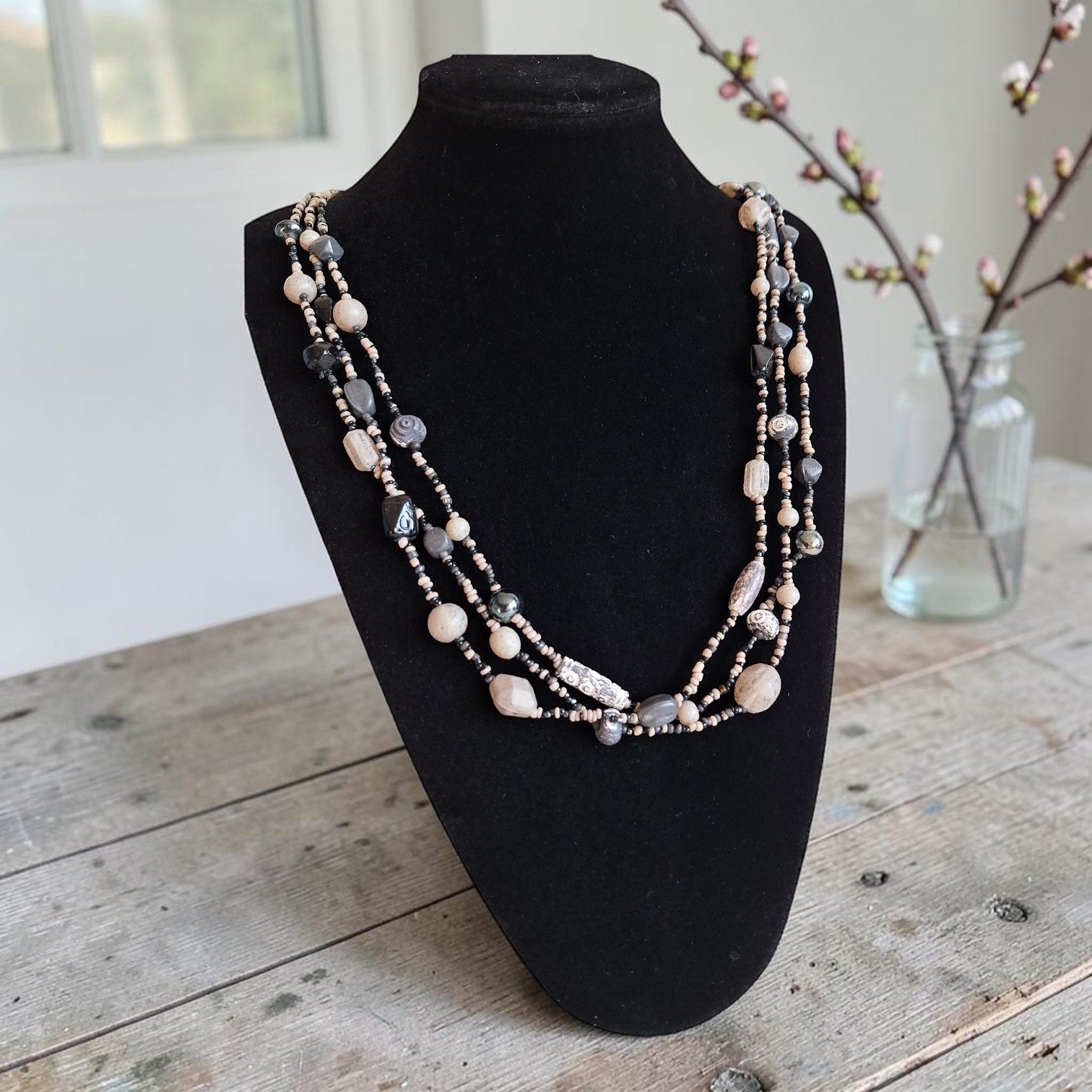 Vintage drierijige boho-halsketting met beige, roze en antracietgrijze kralen in verschillende vormen, lengte 76 cm.
