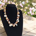 Vintage meerlaagse boho-halsketting met bruine houten kralen en witte schelpschijven, lengte 55 cm.
