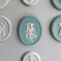 Ovaal zeegroen Villeroy & Boch Mettlach wandmédaillon met een wit reliëf van een omhelzend koppel en een decoratieve touwrand.