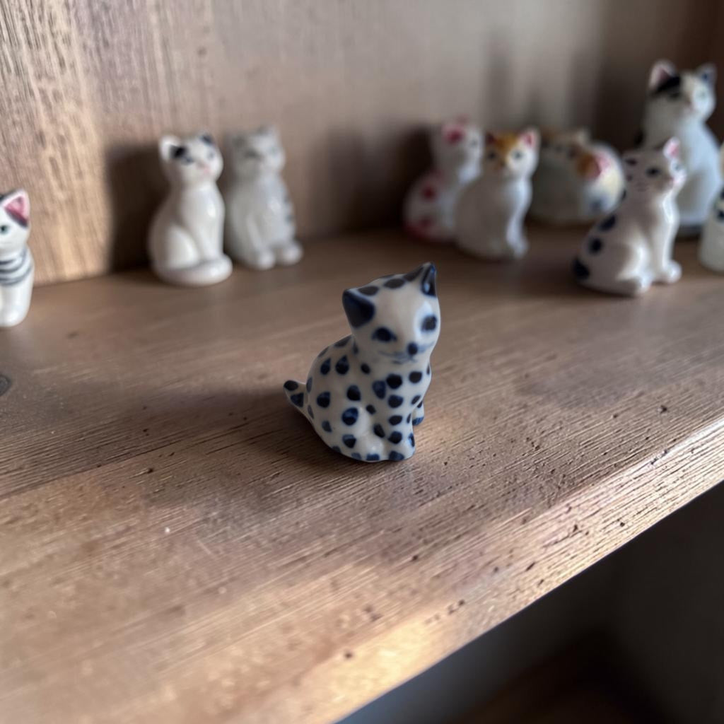 Handbeschilderd miniatuur kattenbeeldje van wit keramiek met kobaltblauwe stippen, zittende houding, ca. 4,5×2,5×3,5 cm.