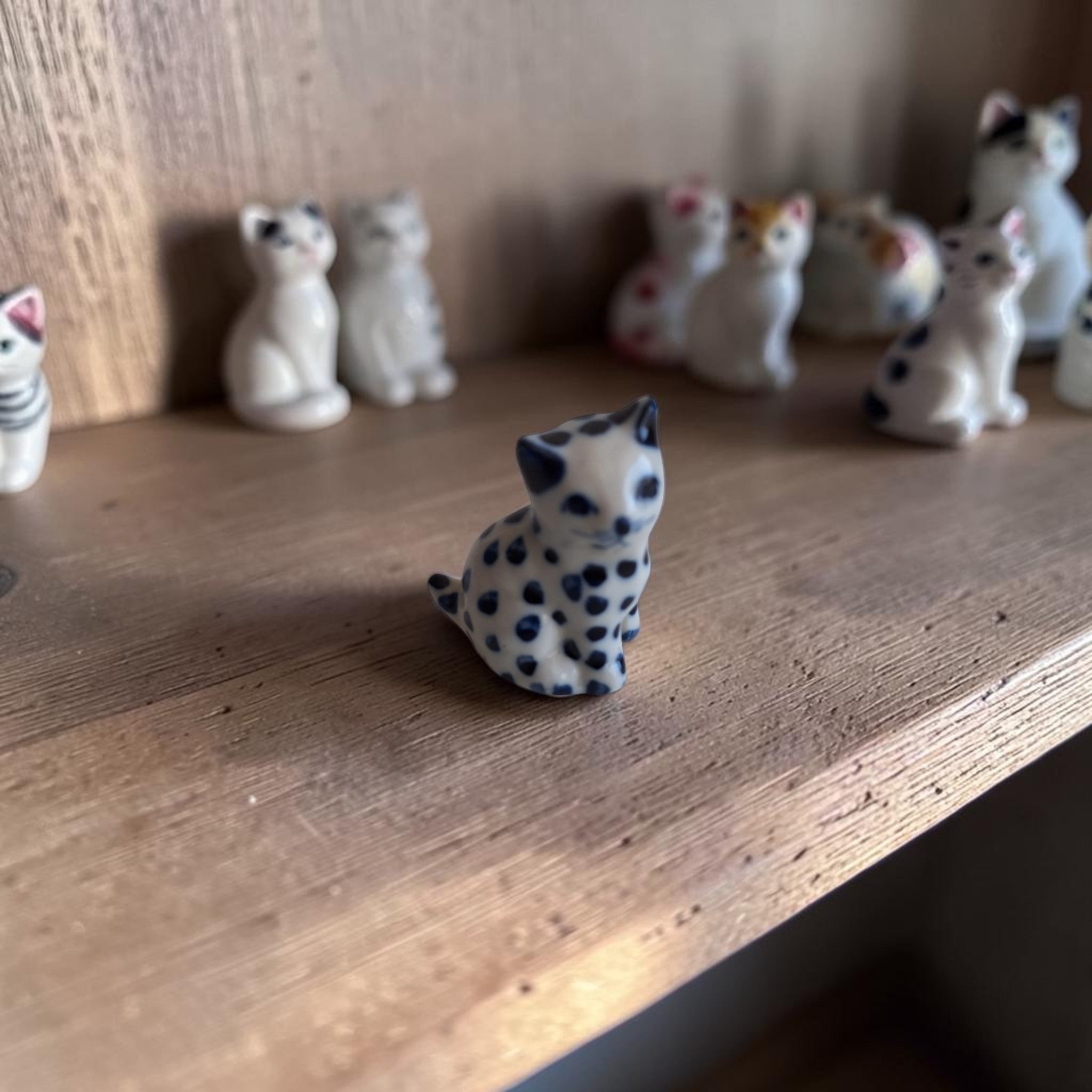 Handbeschilderd miniatuur kattenbeeldje van wit keramiek met kobaltblauwe stippen, zittende houding, ca. 4,5×2,5×3,5 cm.