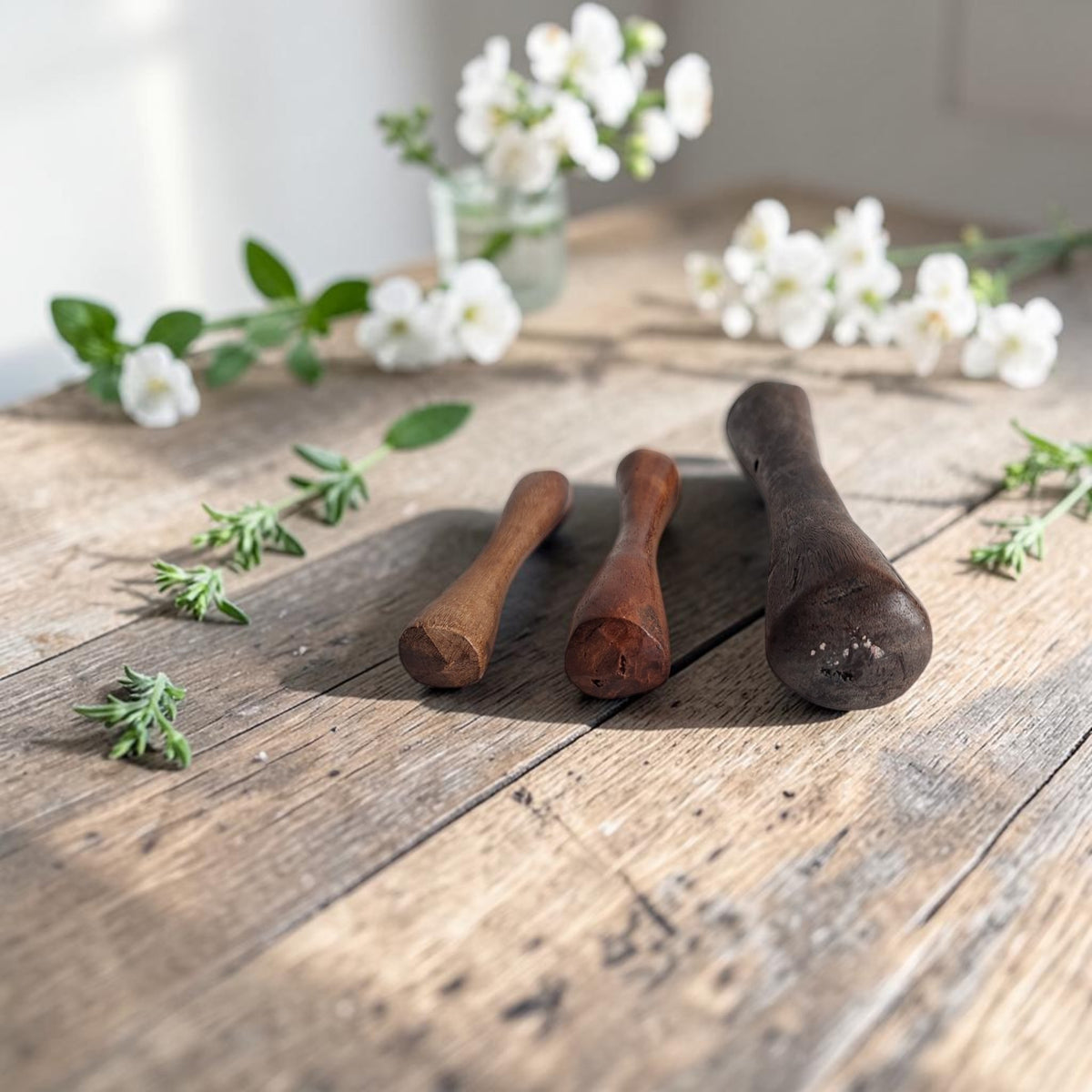 Set van drie handgemaakte houten Afrikaanse vijzelstampers in verschillende lengtes, bedoeld voor een kleine tafelvijzel.
