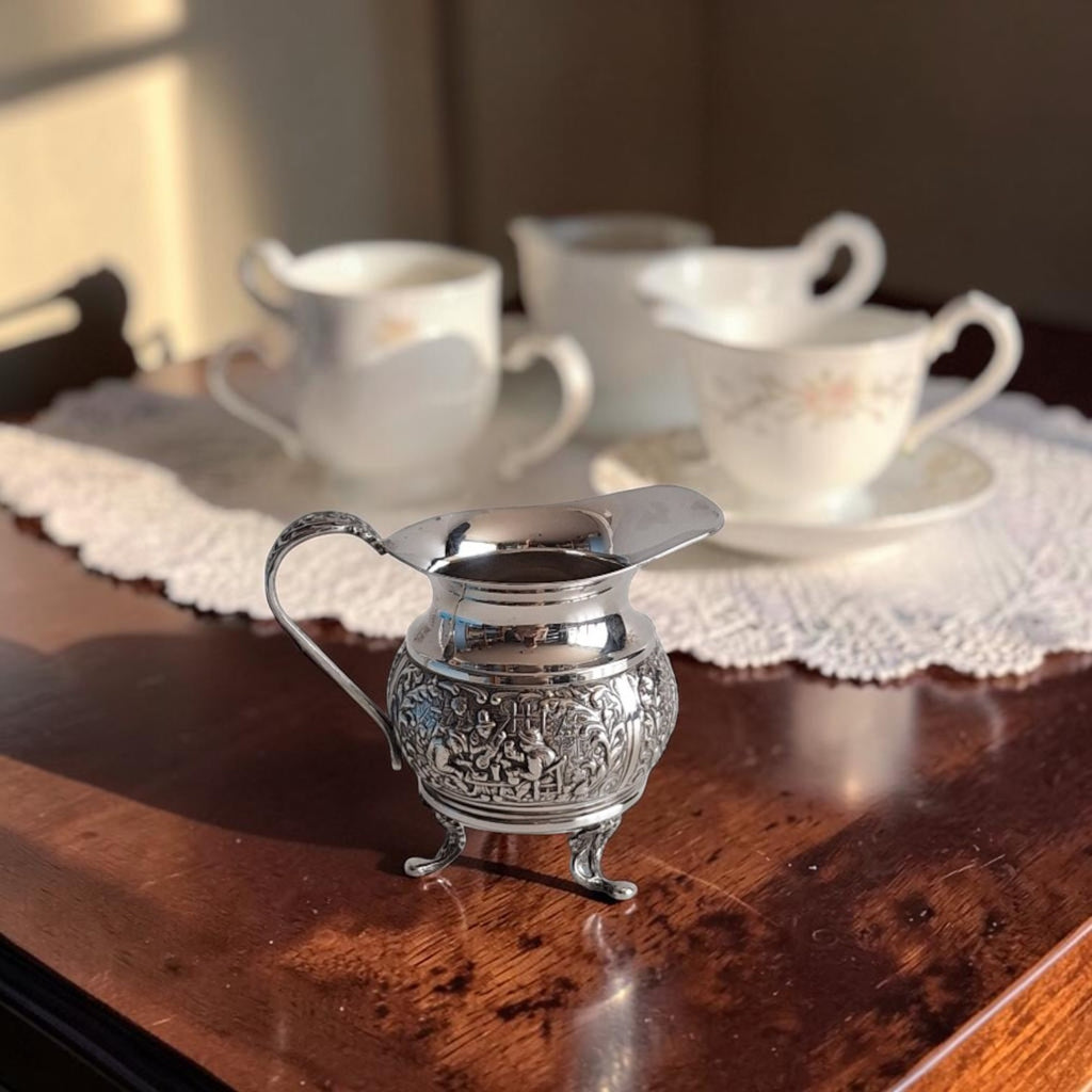 Verzilverd melkkannetje van H. Hooijkaas Schoonhoven met repoussé reliëf van Oud-Hollandse herbergscènes, gemerkt HH 90.