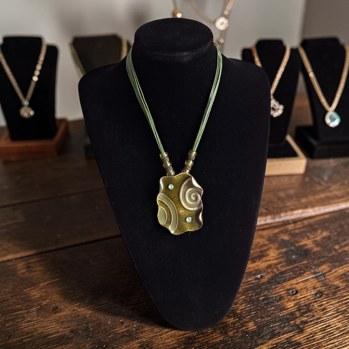 Handgemaakt bohemian collier met bronskleurige hanger en gevlochten groene koorden, totale lengte 51cm
