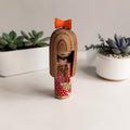 Miniatuur Sosaku Kokeshi met rood-wit cilindrisch lichaam en oranje strik op het hoofd, h8,5 x b3 x d3 cm, Japanse volkskunst.