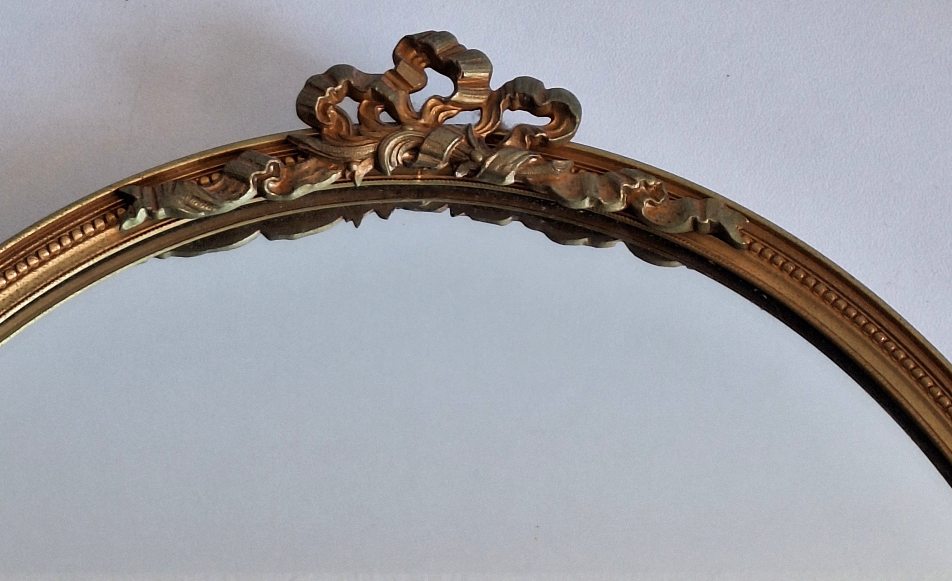 Ovale wandspiegel - neoclassicistisch goudkleurig met strikornament - 33 x 25,5 cm